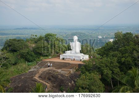 Sculpture of the sitting Buddha against the background of a cloudy landscape. The Mango Plateau in Mikhintale. Sri Lanka