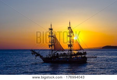 Two-masted sailing ship on the background of the setting sun.