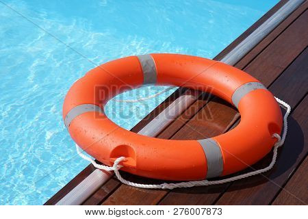 The Red Life Ring Lies On The Wooden Floor Of The Swimming Pool. Life Cycle, Floating Above The Sunn