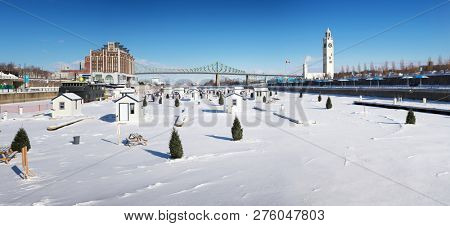 A panorama of the frozen St Lawrence river and Jacques Cartier Bridge Montreal. In winter, temporary fishing huts are erected on the ice. Visible signs say 'Old Port' which is the name of the location