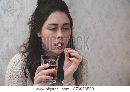 A Young Girl Wrapped In A Blanket And During Illness And Checks The Temperature Looking At The Therm