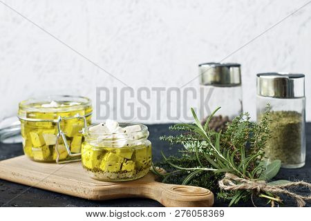 Marinated Feta In A Glass Jar And Spices Against White Background.
