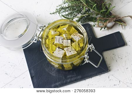 Marinated Feta In A Glass Jar And Spices Against White Background.