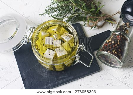 Marinated Feta In A Glass Jar And Spices Against White Background.
