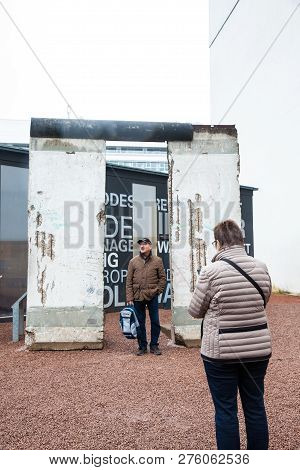 Berlin, Germany - March, 2018: Tourists Looking At A Piece Of The Berlin Wall At The  Entrance Of Th
