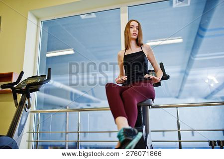 Young Sport Girl Workout In Gym. Fitness Woman Doing Exercises On Stationary Bicycle.