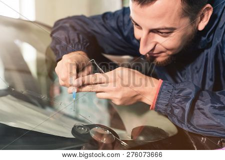 Close-up Of A Professional Windshield Repairman Fills A Crack In The Glass With A Special Polymer Th