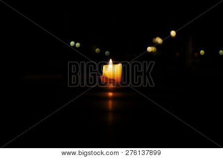 A Lonely Lit Candle With Reflection On A Wooden Surface