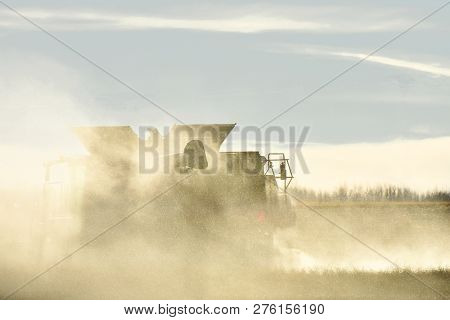 An Image Of A Combine Harvester Creating A Cloud Of Dust During A Late Harvest.