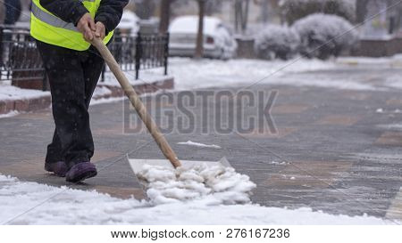 Man With Snow Shovel Cleans Sidewalks In Winter.