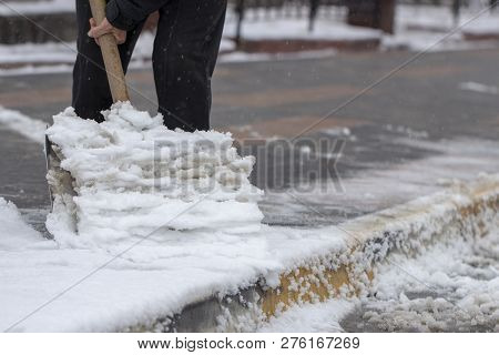 Man With Snow Shovel Cleans Sidewalks In Winter.