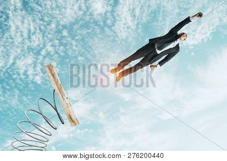 Businessman Lauching Off Big Spring On Sky Background With Clouds. Startup And Success Concept
