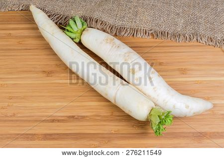 Top View Of Two Fresh Washed Daikon Radish With Torn Off Haulm On A Wooden Bamboo Surface With Sackc