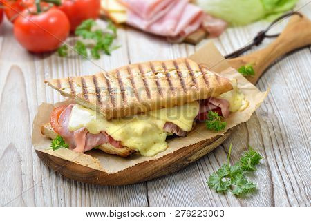 Grilled And Pressed Toast With Smoked Ham, Cheese, Tomato And Lettuce Served On Sandwich Paper On A 