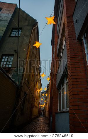 Narrow Rozena Street In Old Town Riga, Latvia With Stars Garland. Christmas Decoration On The Europe