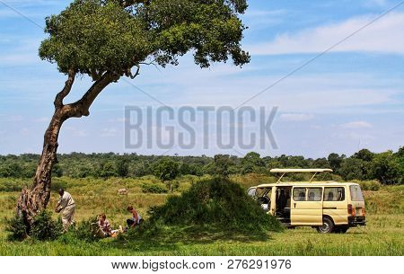 Masai Mara-kenya/october 2013: Group Of Tourists Having Lunch Break Under Tree In The Savannah Plain
