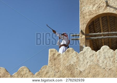 Zekreet - Qatar / December 2010: Young Man Holding His Rifle While Standing On High Wall In A Tradit