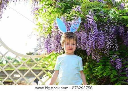 Rabbit Child In The Garden. Kid Stands On Vintage Background In Park. Beautiful Flower Bushes Behind