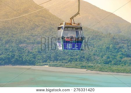 Ngong Ping Cable Car With Tourists Over Harbor, Mountains And City Background, To Visit The Tian Tan