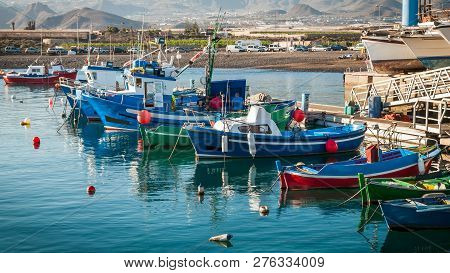 Panoramic View Of Moored Colourful Fishing Vessels And Boats At Dockside On Background Of Hilly Shor