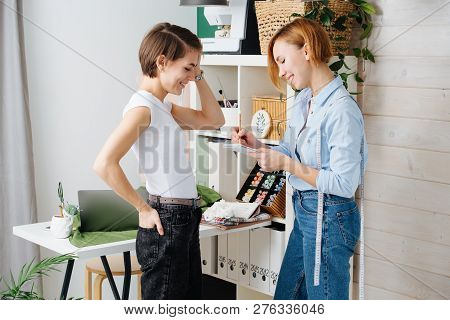 Young Female Fashion Designer Taking Measurements Of A Woman To Design New Clothes. They Both Have S
