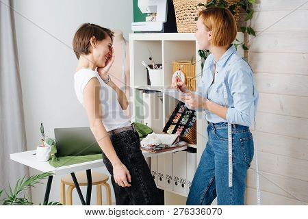 Young Female Fashion Designer Taking Measurements Of A Woman To Design New Clothes. They Both Have S