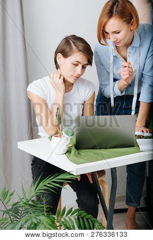 Young Female Fashion Designer Reviewing Clothing Styles With A Customer To Choose Design. They Both 