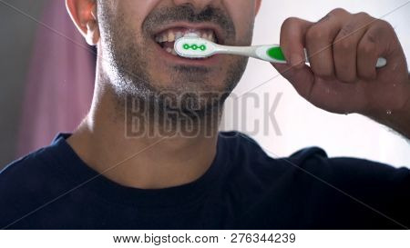 Reflection Of A Young Man Brushing His Teeth In Bathroom. Close-up Image Of A Man Brushing The Teeth