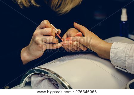 Manicurist Applying Red Nail Varnish. Manicure Master Painting Female Finger With Close Up. Manicure