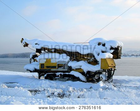 Snow And Ice Covered Strong Yellow Machine In The Winter Freezing Day. River Danube Environment, Fut