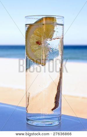 frisch Glas Blase Wasser mit einer Scheibe Zitrone am Strand