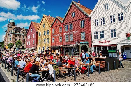 Bergen, Norway - January 26, 2010: People Sit In Street Cafe At Colorful Hanseatic Buildings On Sunn