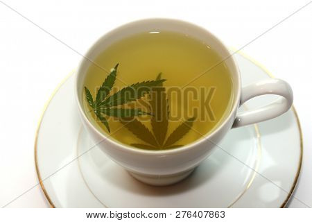 Cannabis Tea. Marijuana Tea. Hemp Tea with a Marijuana Leaf in a white Tea Cup. Isolated on white. Room for text. 