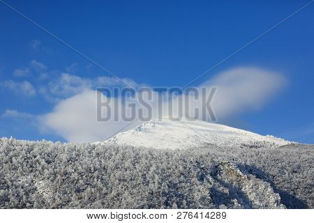 Rtanj - Clouds On A Snowy Mountain Peak And The Base Forest On A Blue Sky