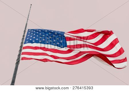 United States Flag Flying At A Half-staff Waving Against Gray Sky