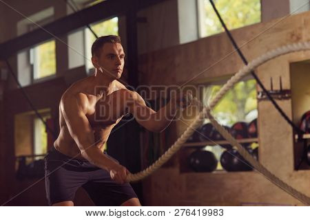 Fit, Sporty And Athletic Sportsman Working In A Gym. Man Training Using Battle Ropes. Sports, Athlet