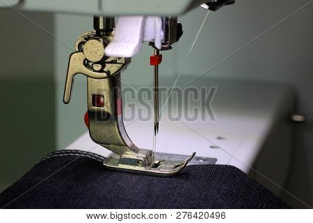 Black Fabric Under A Pressing Foot Of A Sewing Machine With Double Needle. Light Blue Thread.