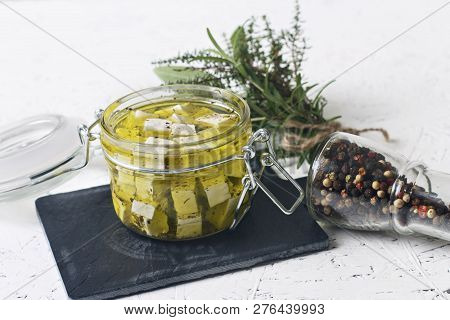 Marinated Feta In A Glass Jar And Spices Against White Background