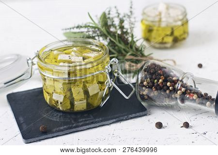 Marinated Feta In A Glass Jar And Spices Against White Background