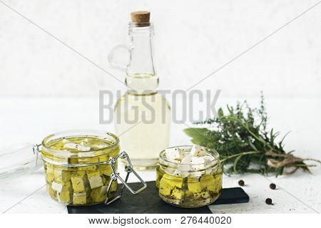 Marinated Feta In A Glass Jar, Spices And Flavored Olive Oil On A Wooden Background