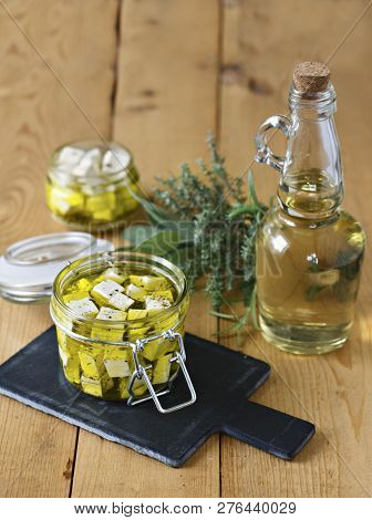 Marinated Feta In A Glass Jar, Spices And Olive Oil On A Wooden Background