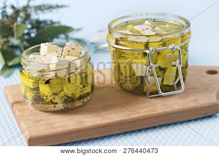 Marinated Feta In A Glass Jar And Spices Against Blue Background