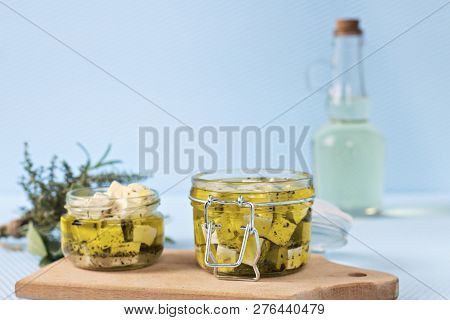 Marinated Feta In A Glass Jar And Spices Against Blue Background