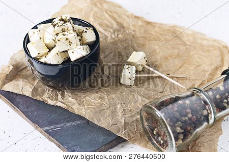 Marinated Feta In A Plate On A Wooden Board With Spices On A White Background