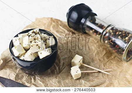 Marinated Feta In A Plate On A Wooden Board With Spices On A White Background