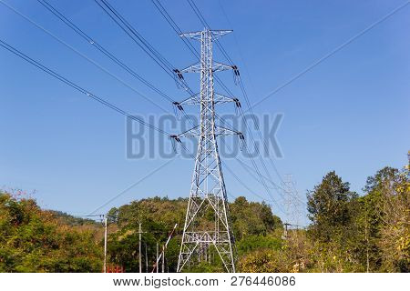 High Voltage Transmission Towers With Mountain Background And Blue Sky