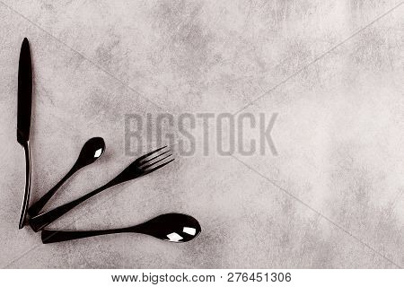 Modern Black Cuttlery On Grey Surface From Above With Copy Space.