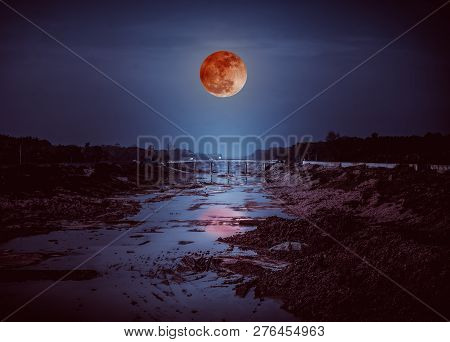 Landscape Of Night Sky With Many Stars. Beautiful Blood Moon Above Along Deep Canal In Rural Area. O