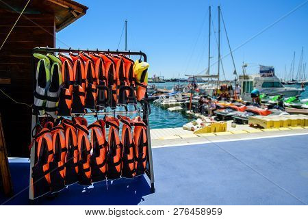 Many Life Jackets On The Beach, Safe Motorboat Rental, Row Of Life Jacket Hanging For Tourist Servic