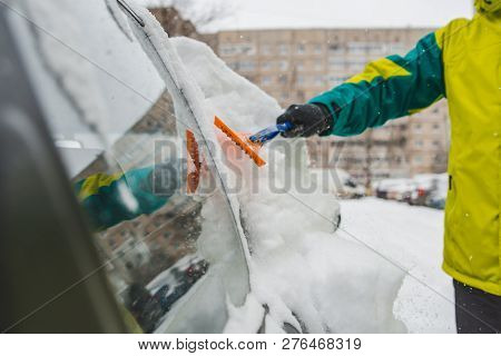 Man With Scrapper Cleaning Car Out Of Snow. Snow Storm